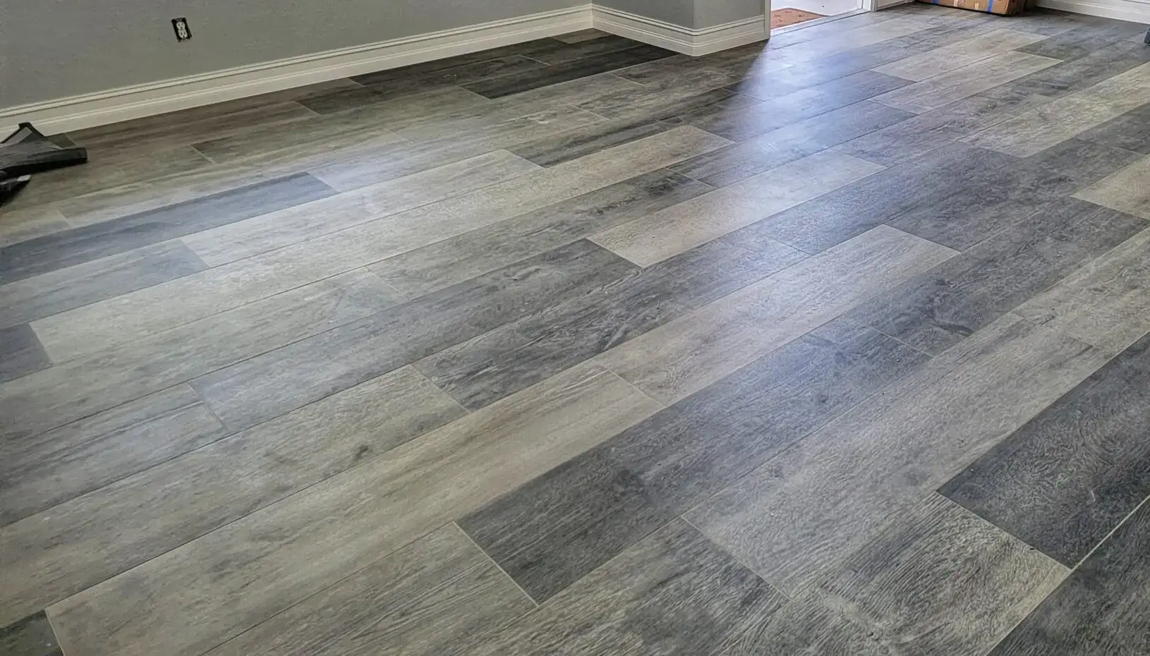 Large-format porcelain tile plank look wood flooring completed in Cape Coral with new baseboards and interior paint